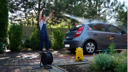 man maakt auto schoon met hogedrukreiniger